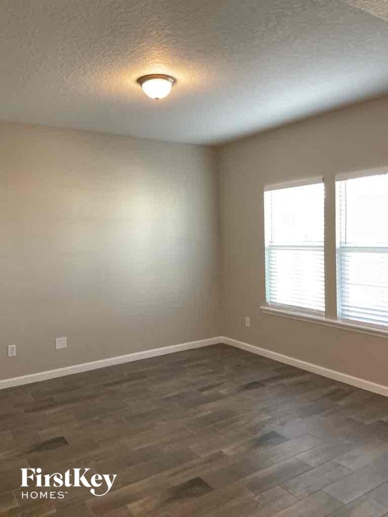 an empty living room with a hard wood floor and two windows