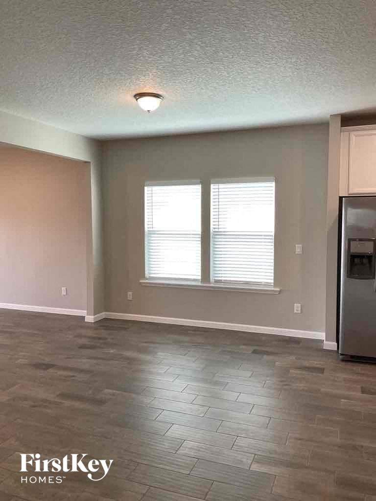 an empty living room with a refrigerator and a window