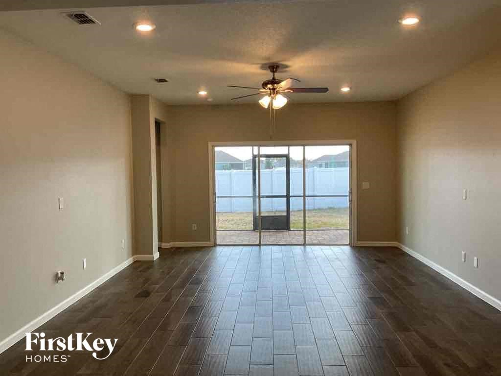 an empty living room with a ceiling fan and sliding glass doors