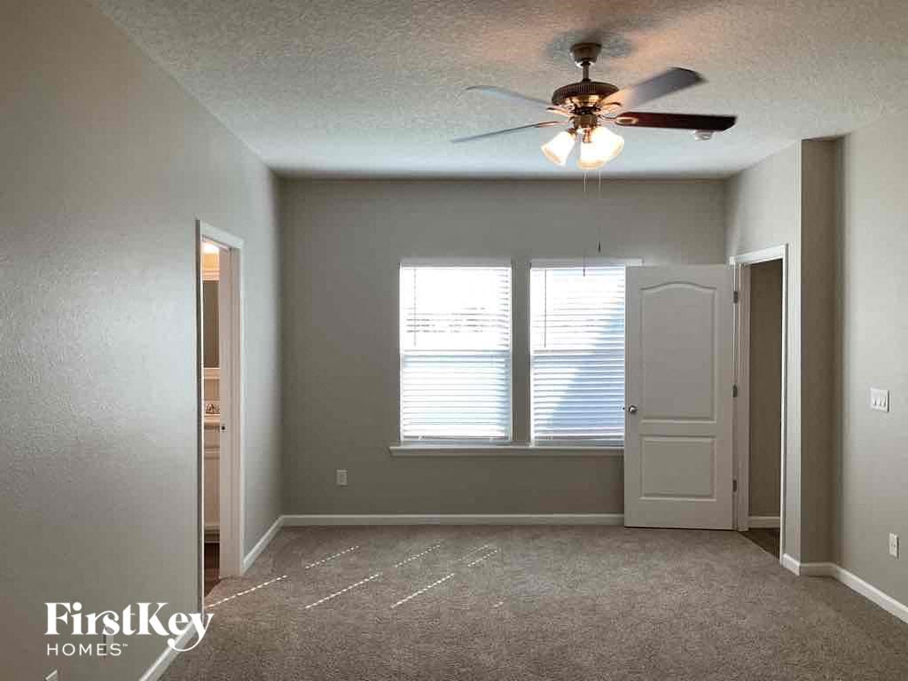 an empty living room with a ceiling fan and window
