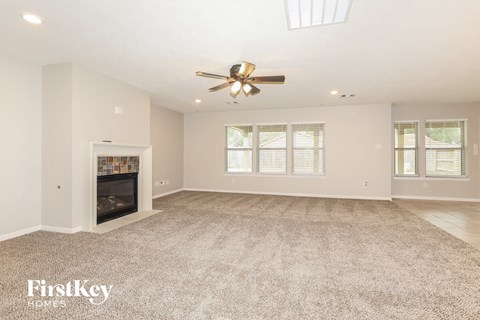 A spacious living room with a fireplace and a ceiling fan.