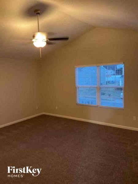 an empty bedroom with a ceiling fan and a window