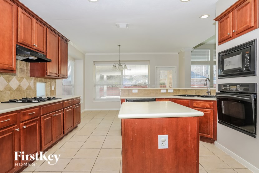 A kitchen with wooden cabinets and a white island.