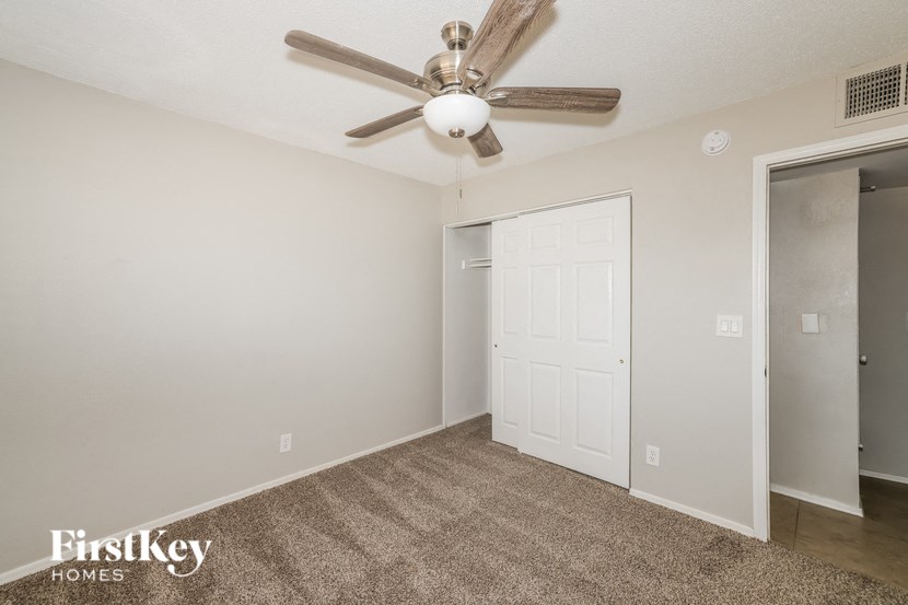 a bedroom with a ceiling fan and a door to a closet