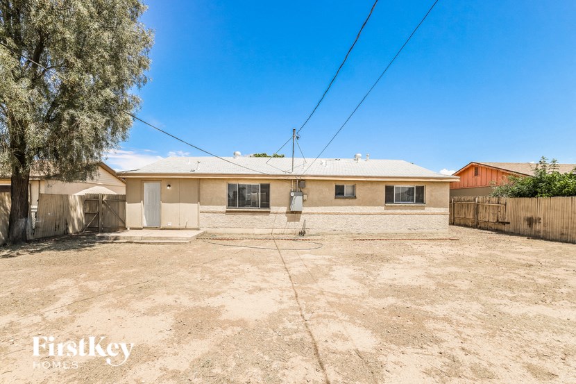 a home with a dirt lot and a house with a fence