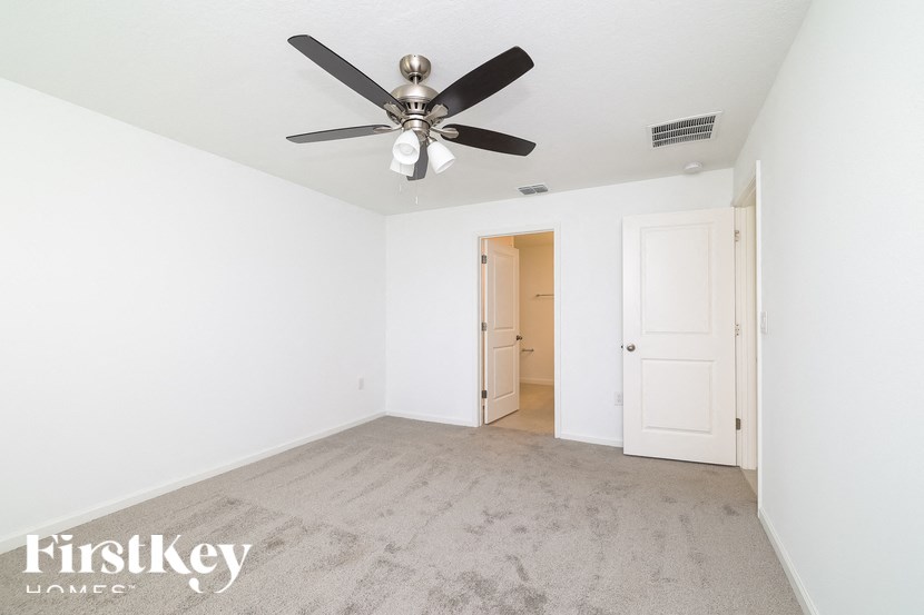 A room with a ceiling fan and carpeted floor.