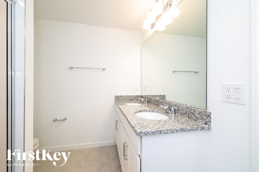 A bathroom with a granite countertop and a large mirror.