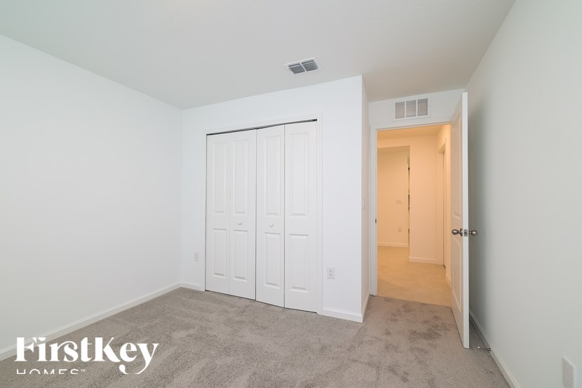 A bedroom with a white door and a carpeted floor.
