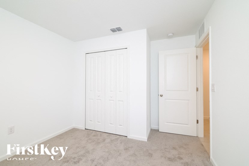 A bedroom with a white door and a carpeted floor.
