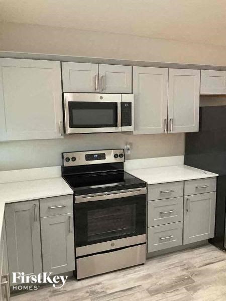 a kitchen with white cabinets and a stove and a microwave