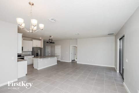 a renovated kitchen and living room with white cabinets and tile flooring