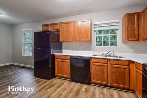 A kitchen with wooden cabinets and a black fridge.