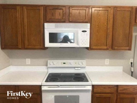 A kitchen with wooden cabinets and a white stove top oven.