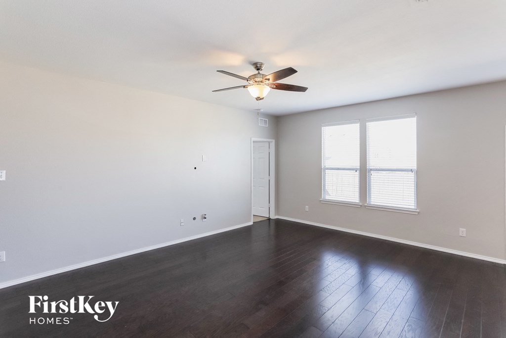 an empty living room with wood floors and a ceiling fan
