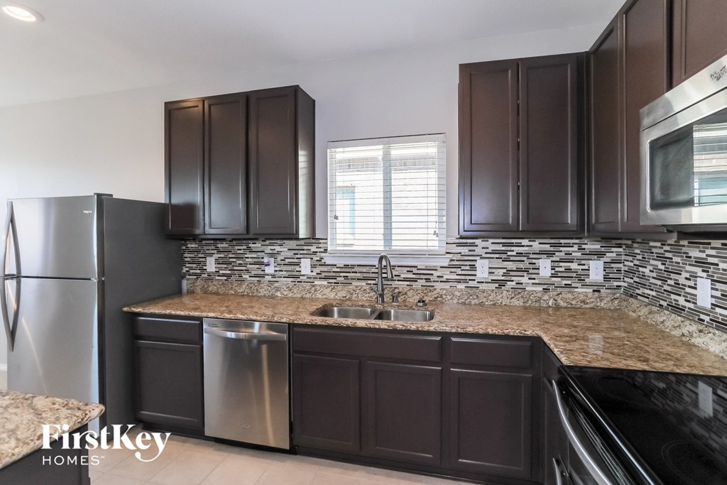a kitchen with brown cabinets and granite counter tops and stainless steel appliances