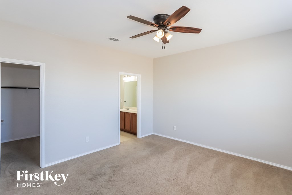 an empty living room with a ceiling fan and a closet
