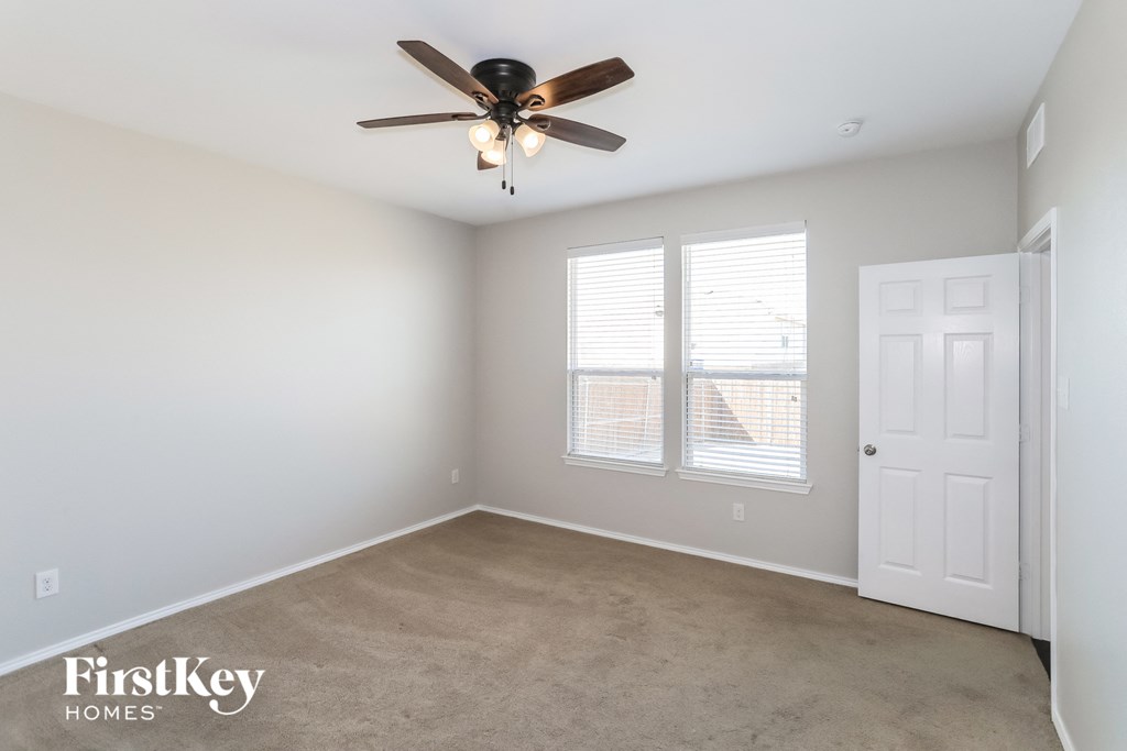 an empty room with a ceiling fan and two windows