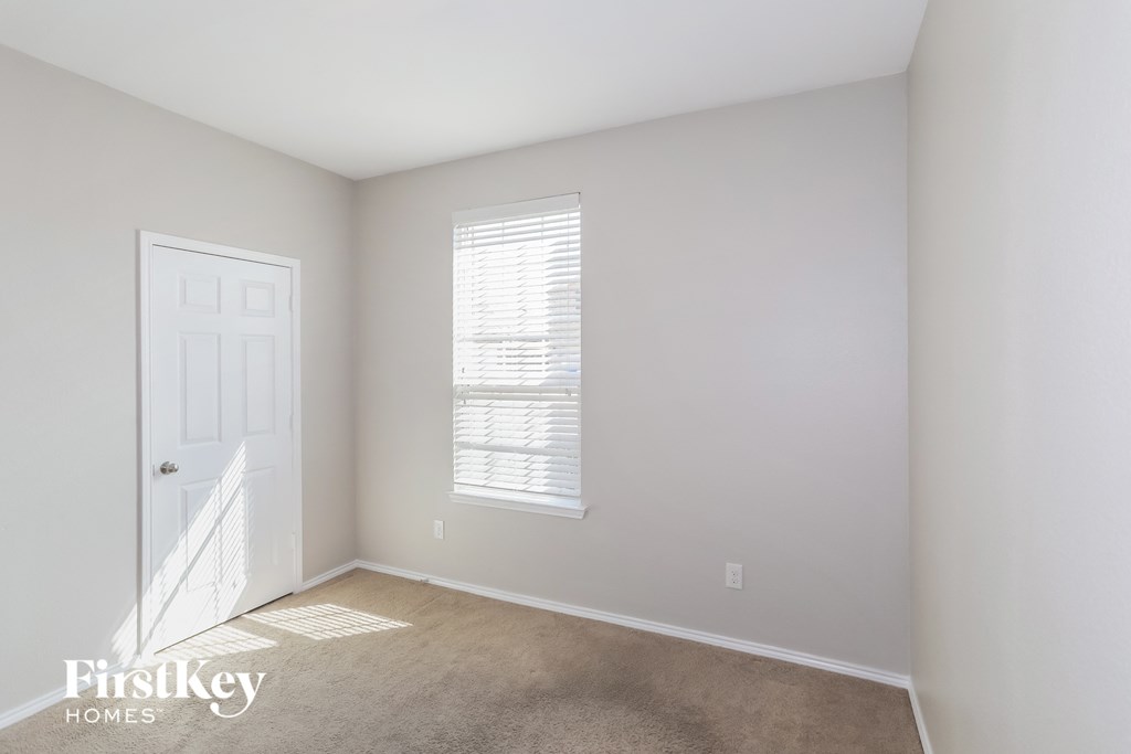 a bedroom with a white door and a window and a carpeted floor