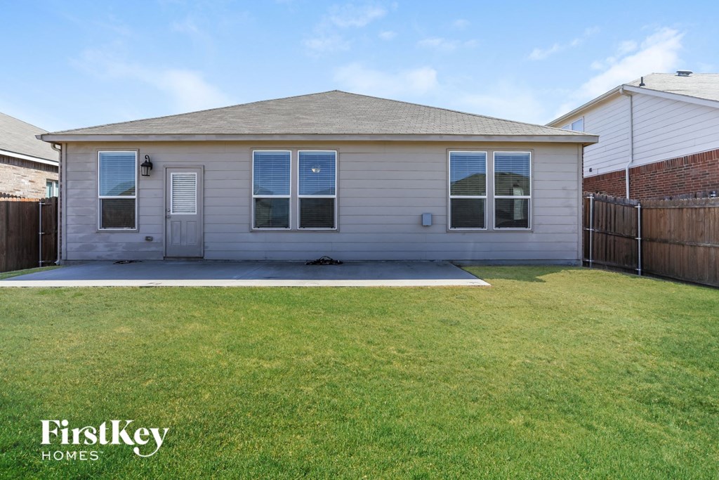 the front of a house with a lawn and a patio
