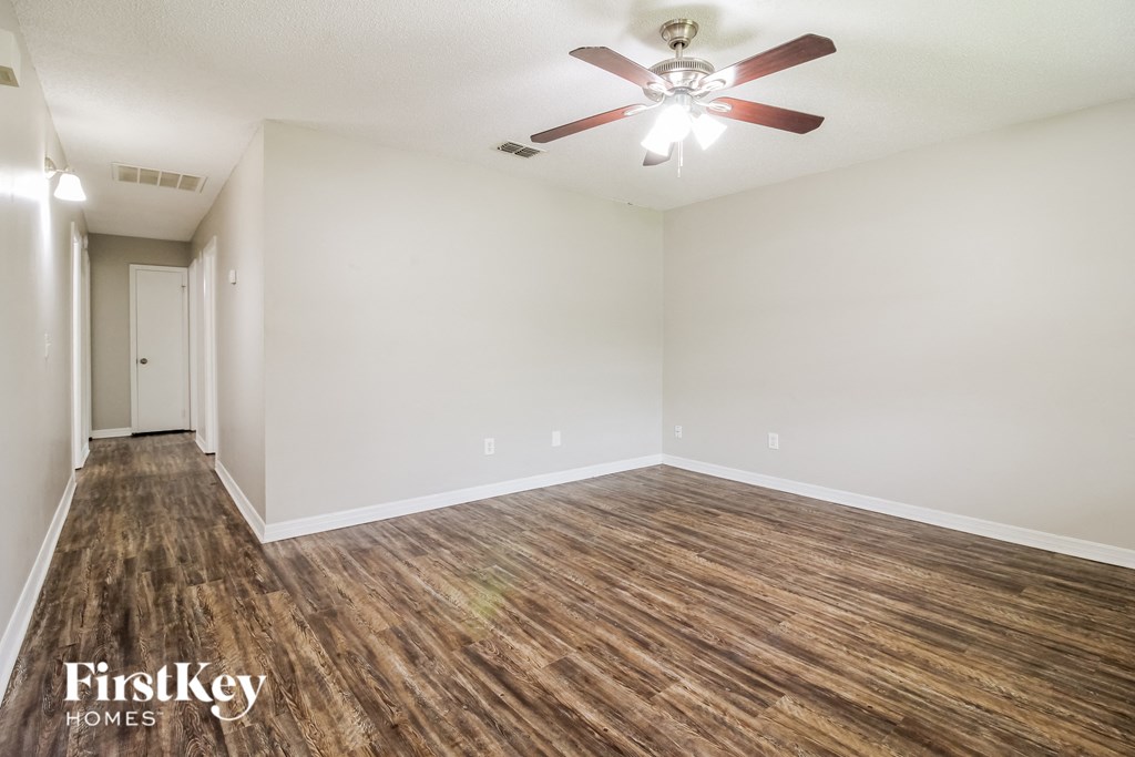 an empty living room with wood flooring and a ceiling fan