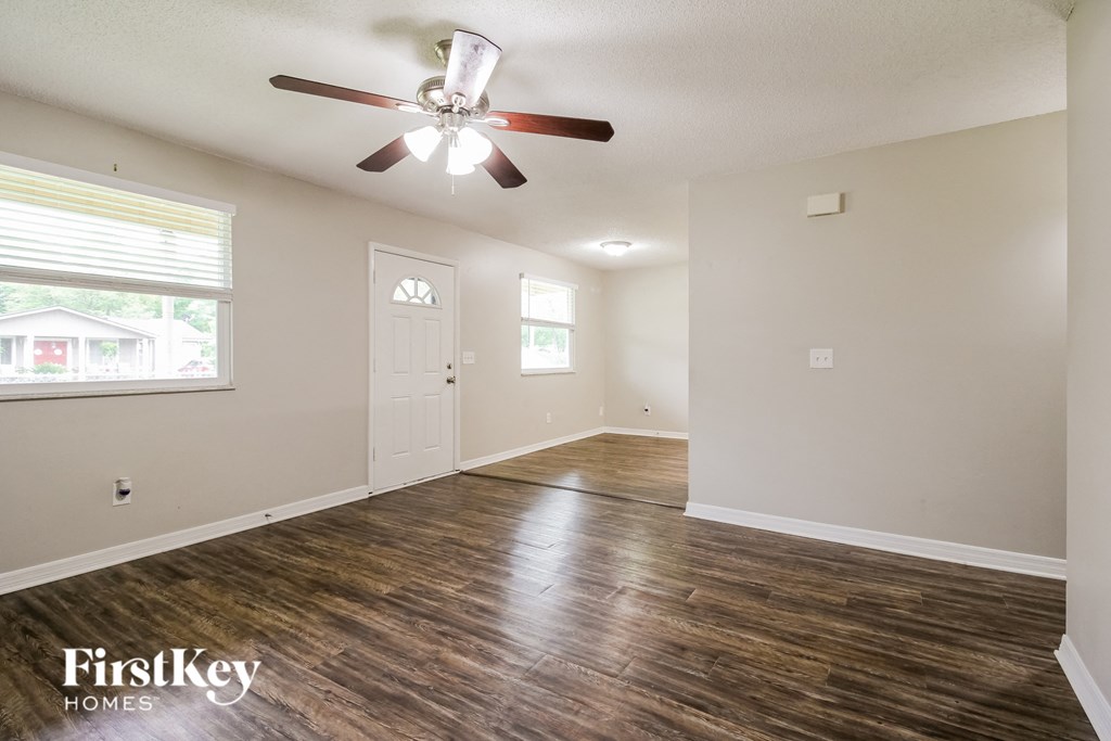 an empty living room with a ceiling fan and a window