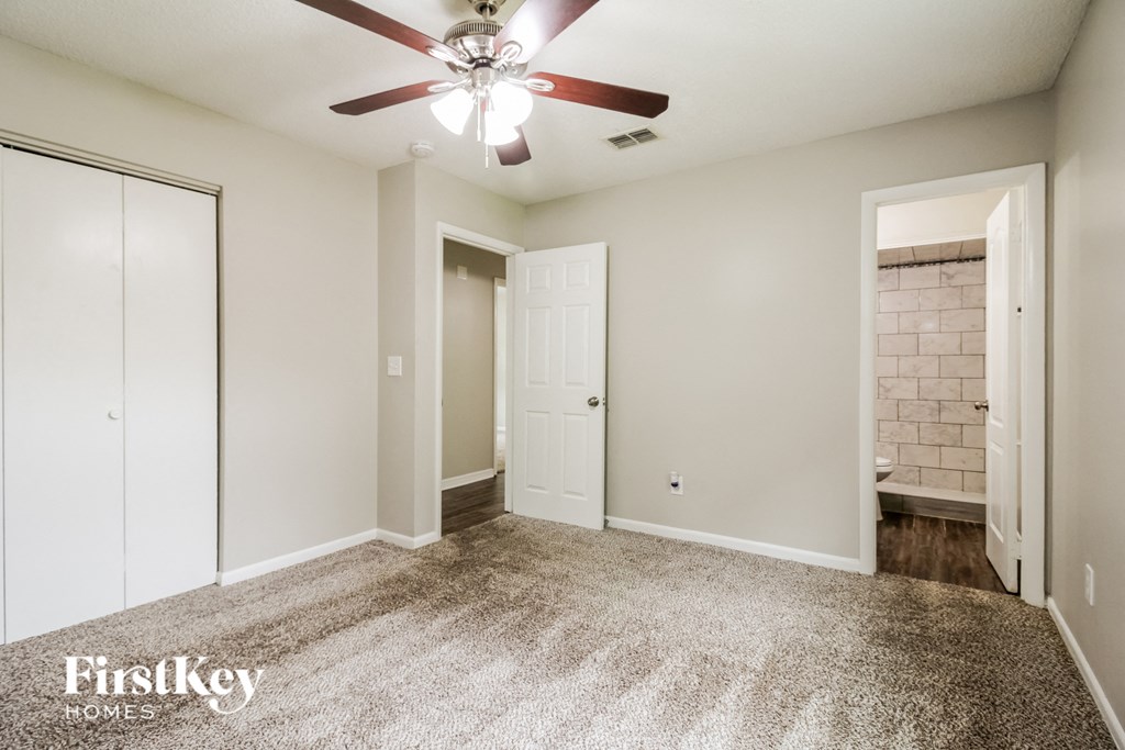 an empty room with a ceiling fan and a bathroom