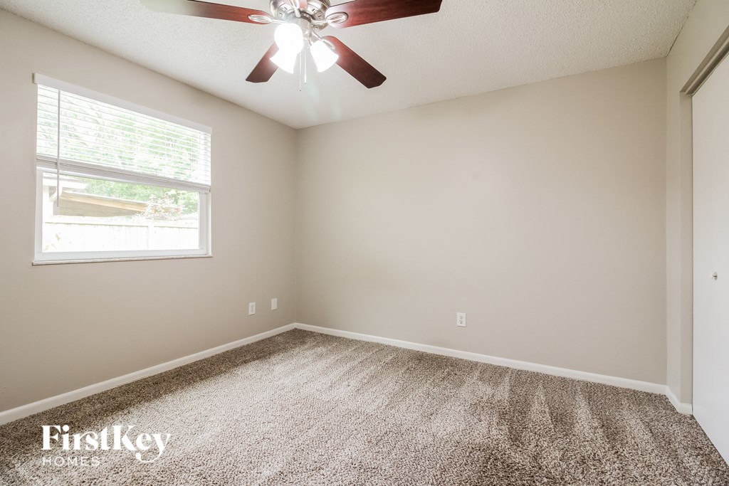 an empty room with a ceiling fan and a window