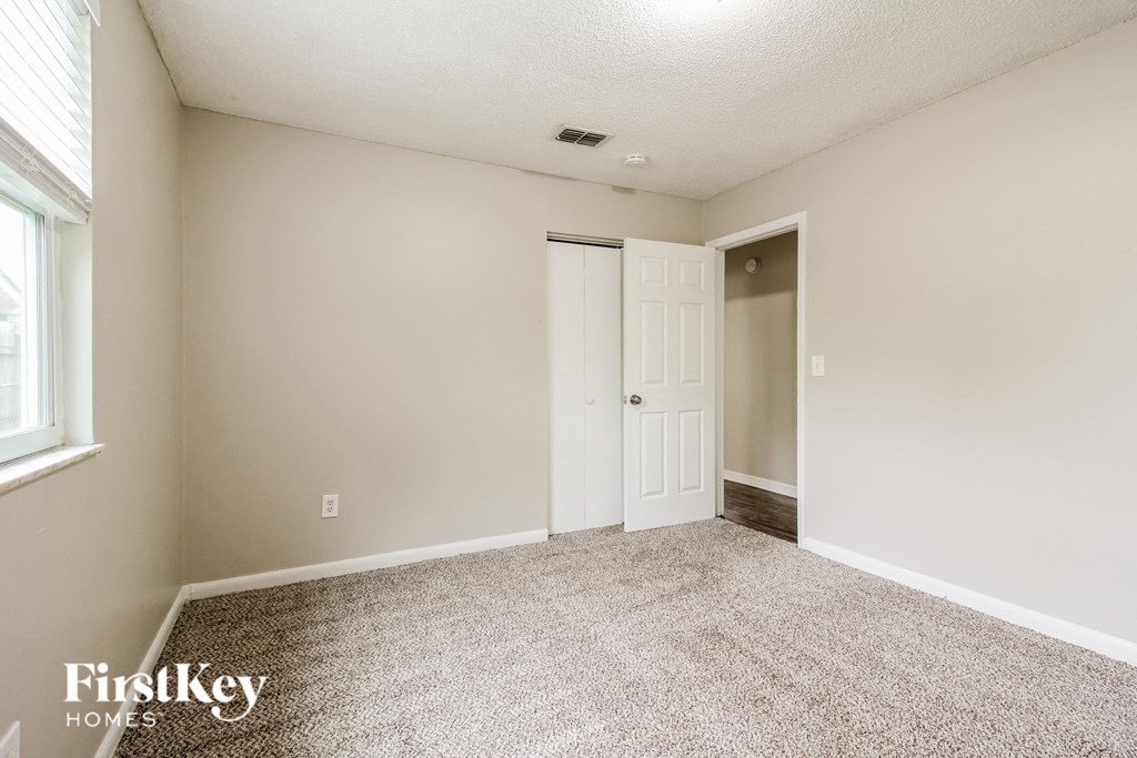 an empty living room with carpet and a door to a closet