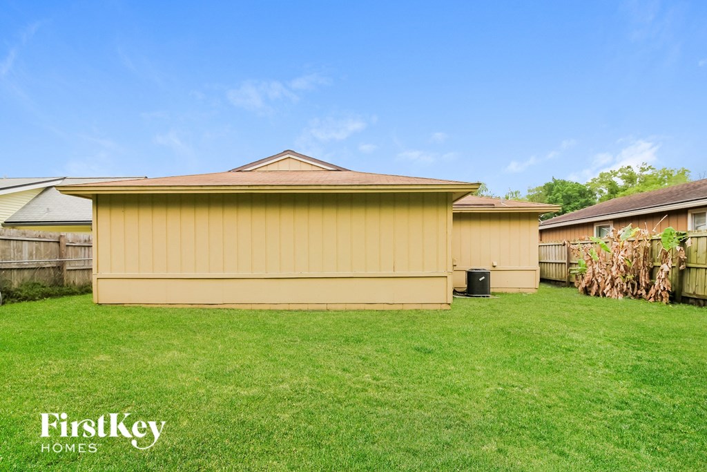 a backyard with a yellow house and a green lawn