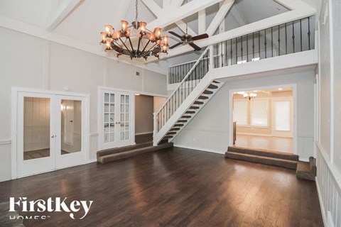 A spacious room with a staircase and a chandelier.