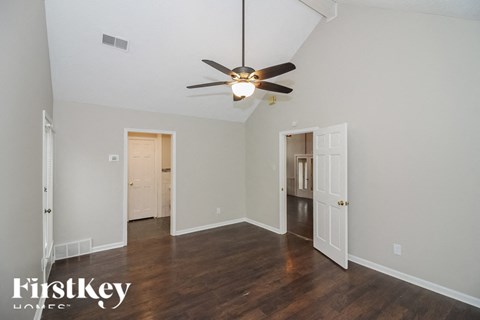 A room with a ceiling fan and wooden floors.