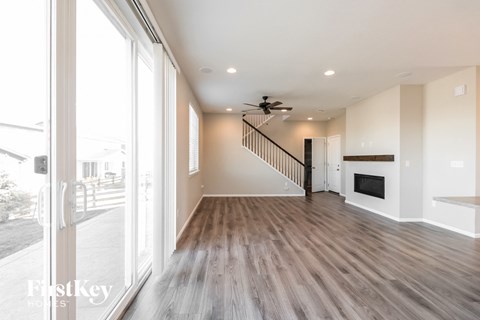 a living room with a fireplace and a hallway with a staircase