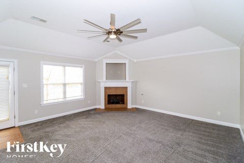 A spacious living room with a fireplace and a ceiling fan.