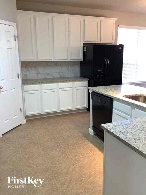 a kitchen with white cabinets and a black refrigerator