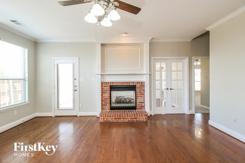 A living room with a fireplace and a ceiling fan.