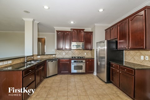 A kitchen with brown cabinets and a black refrigerator.