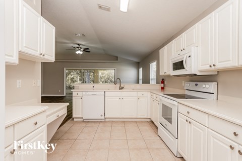 a large kitchen with white cabinets and white appliances