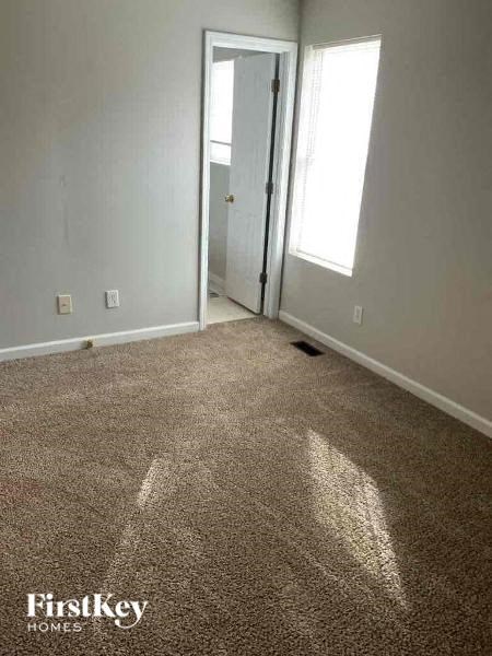 A room with a carpeted floor and a door leading to a hallway.