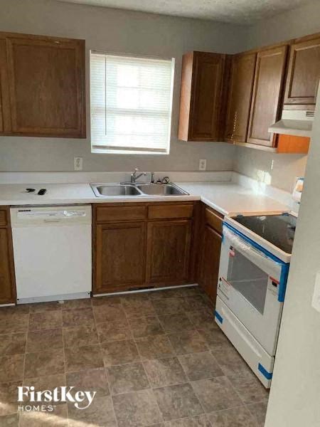 A kitchen with brown cabinets and a white dishwasher.