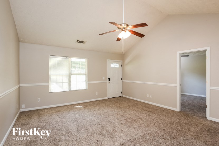an empty living room with a ceiling fan