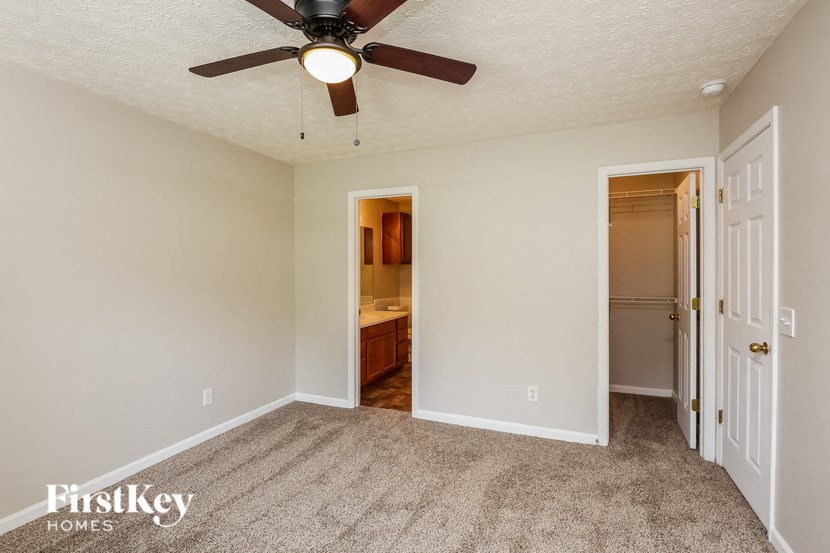 a bedroom with a ceiling fan and a door to a bathroom