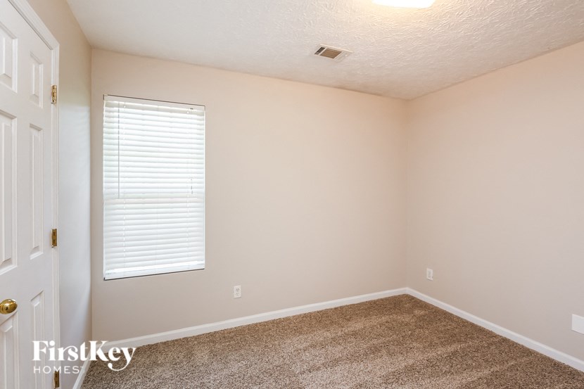 the bedroom of a home with a carpeted floor and a window