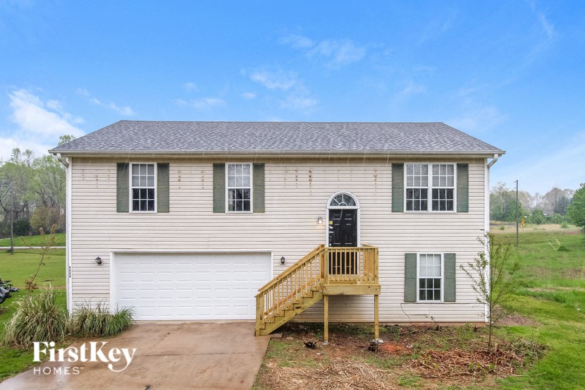 the front of a white house with a porch and a black door