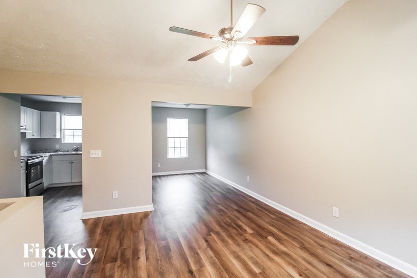 an empty living room with hardwood floors and a ceiling fan