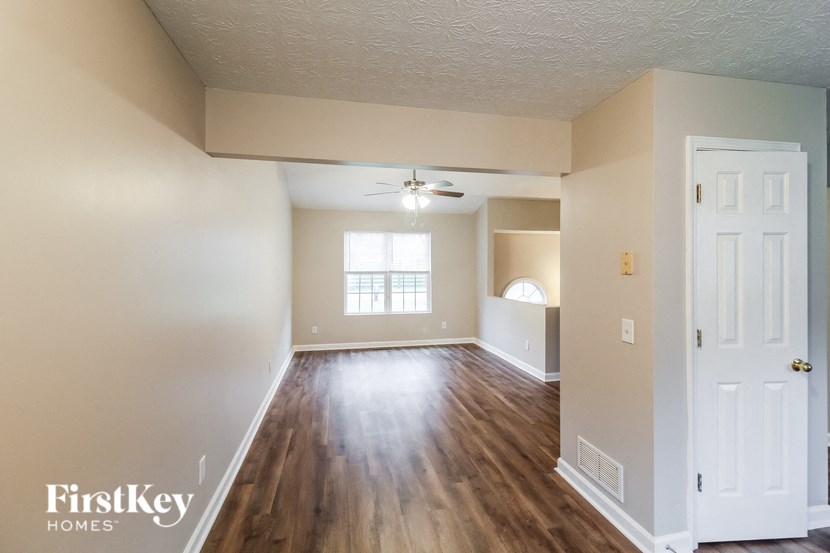 the living room of an empty house with wood flooring and a ceiling fan