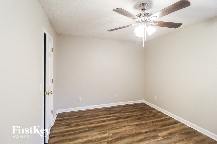 an empty living room with a ceiling fan and wood floors