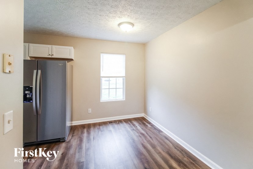 an empty living room with a refrigerator and a window