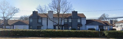 A large house with a grey roof and a white fence.