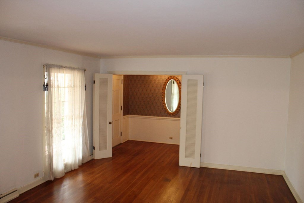 an empty living room with wooden floors and white doors