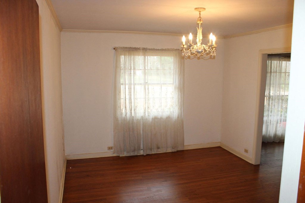 an empty living room with a window and a chandelier